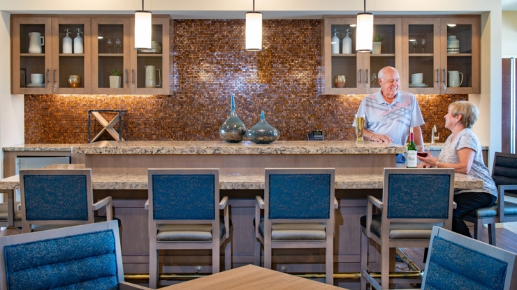 A bright, welcoming lounge where residents enjoy friendly conversation over drinks, fostering community and warmth.