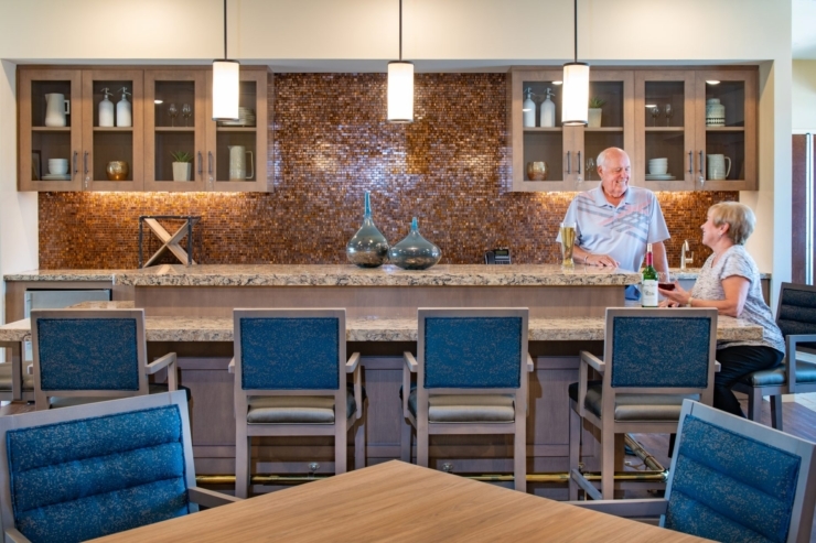 A bright, welcoming lounge where residents enjoy friendly conversation over drinks, fostering community and warmth.