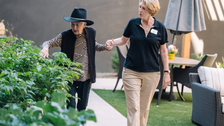 A joyful moment in a landscaped garden, showing warmth and connection between residents and staff.
