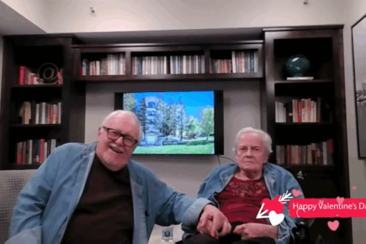 Two residents share a joyful moment, surrounded by books and a vibrant atmosphere, fostering community.