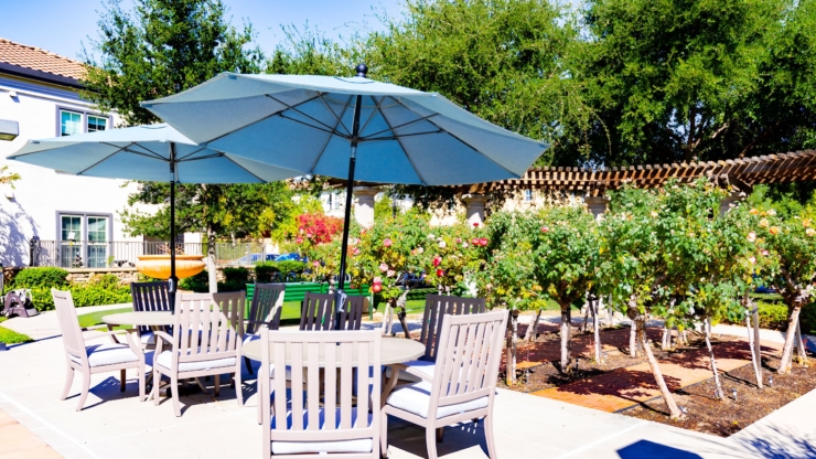 A serene outdoor space with shaded seating, surrounded by vibrant gardens, inviting community gatherings.
