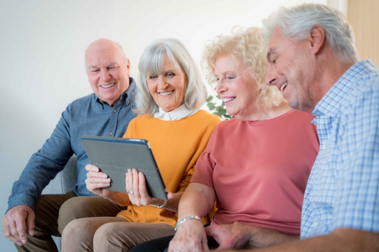 Four friends share laughter and joy while exploring new technology together, fostering community bonds.