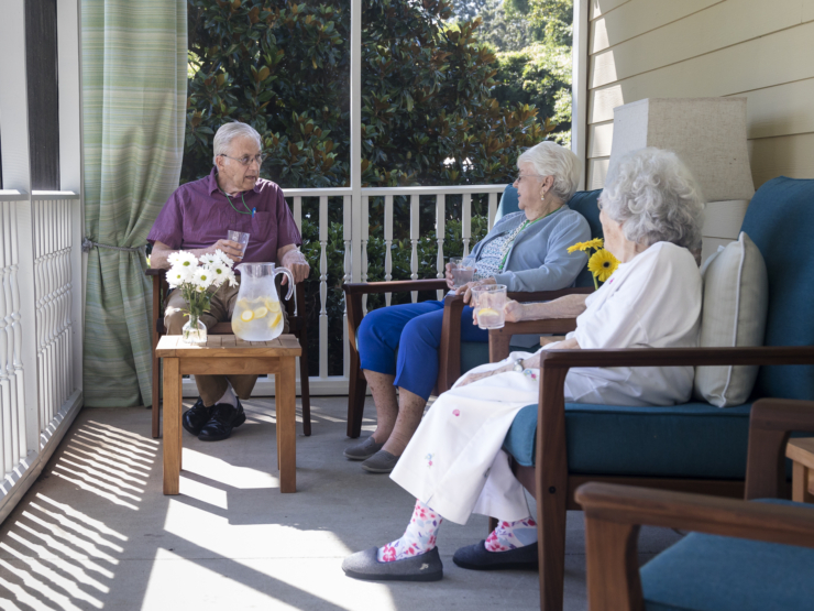 A warm gathering on a sunny porch, where residents enjoy refreshing drinks and heartfelt conversation.