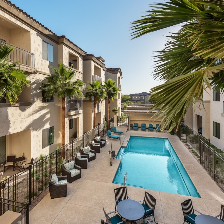 A serene pool area surrounded by inviting seating and lush greenery, fostering community and relaxation.