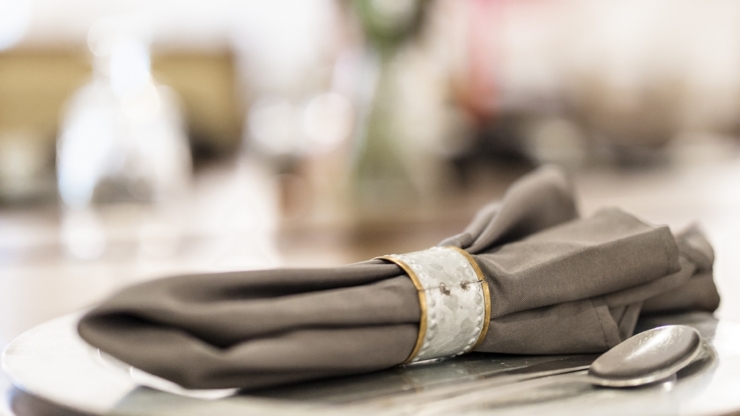 A beautifully set dining table with elegant napkin and floral centerpiece, inviting warmth and community.