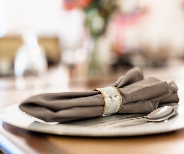 A beautifully set dining table with elegant napkin and floral centerpiece, inviting warmth and community.