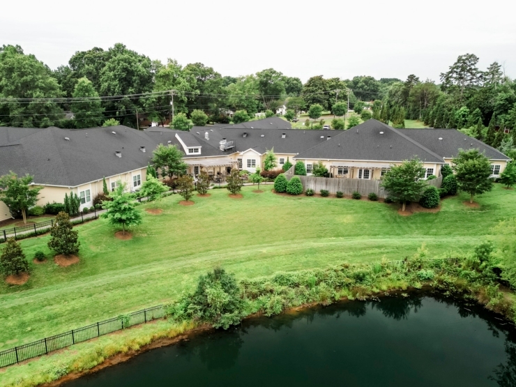 A serene community surrounded by lush greenery and a tranquil pond, promoting comfort and connection.