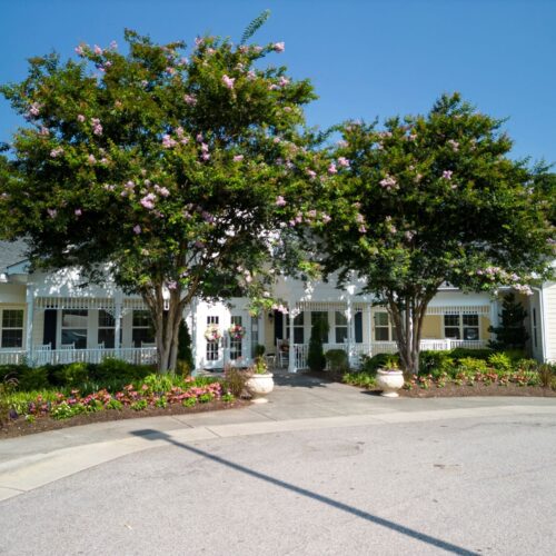 Welcoming entrance surrounded by vibrant flowers and lush trees, radiating warmth and community spirit.
