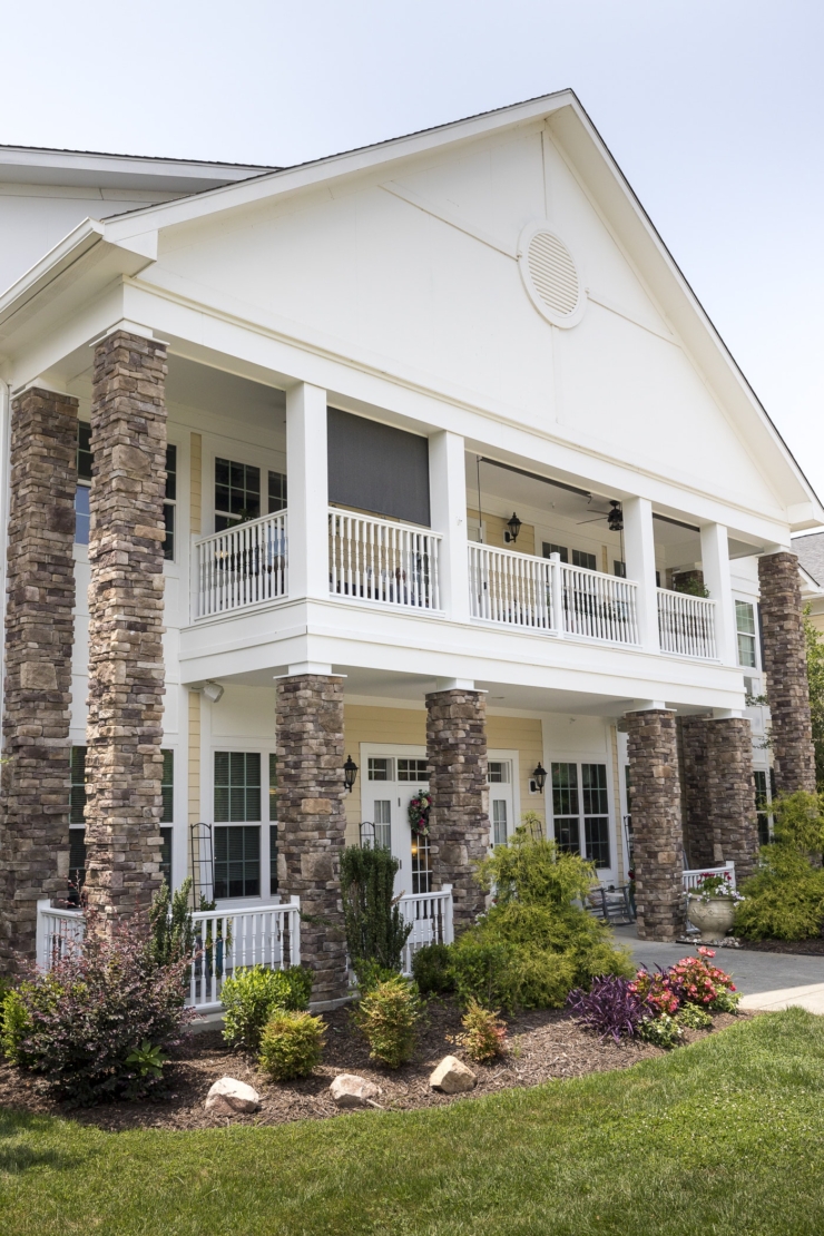 A welcoming entrance with charming stone pillars, surrounded by lush gardens, exudes warmth and community.