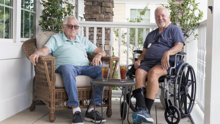 Two gentlemen enjoy refreshing drinks on a cozy porch, surrounded by greenery, radiating warmth and friendship.