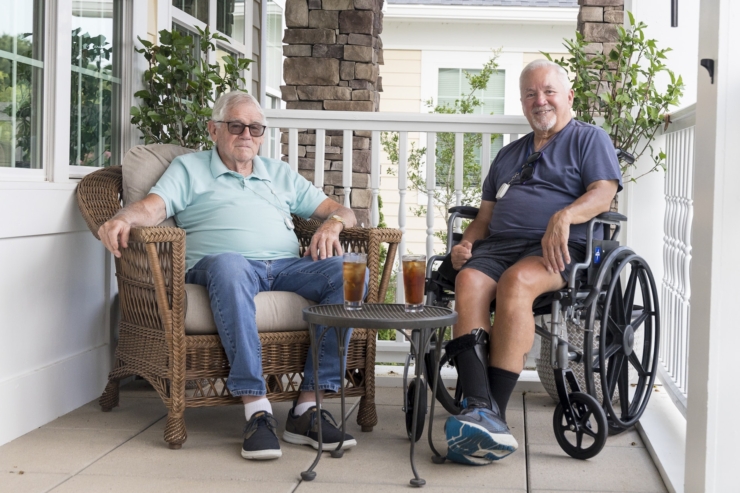 Two gentlemen enjoy refreshing drinks on a cozy porch, surrounded by greenery, radiating warmth and friendship.