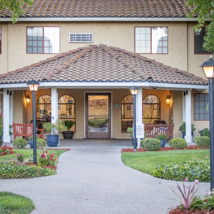 Welcoming entrance surrounded by lush gardens, inviting benches, and a friendly atmosphere for all.