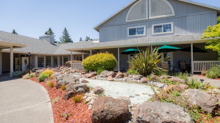 A welcoming outdoor space with lush greenery, inviting seating, and a serene water feature enhances community connection.