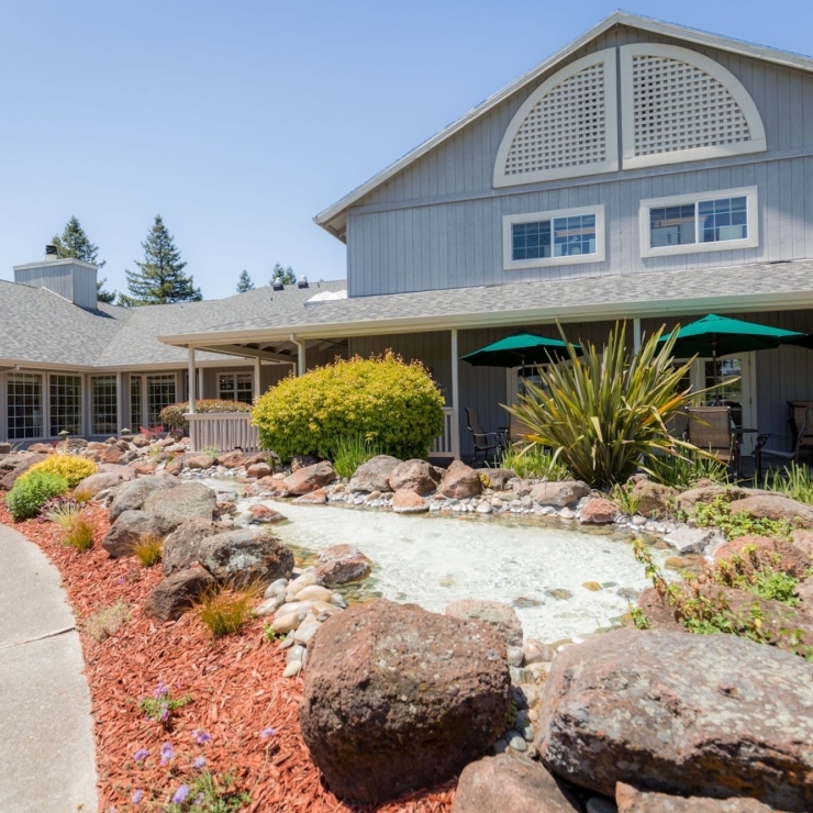 A welcoming outdoor space with lush greenery, inviting seating, and a serene water feature enhances community connection.