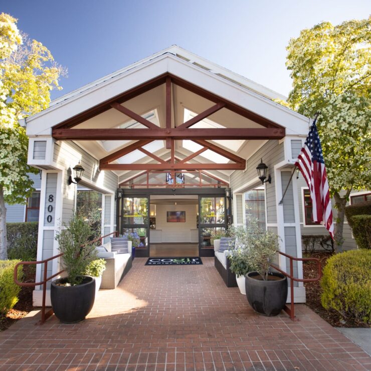 Welcoming entrance with lush greenery, inviting seating, and a warm atmosphere for community living.
