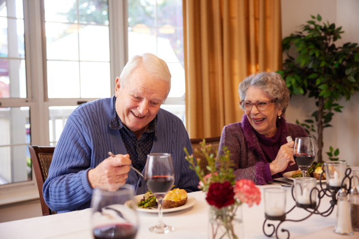 Residents enjoying a cheerful meal together, surrounded by warm colors and blooming flowers.