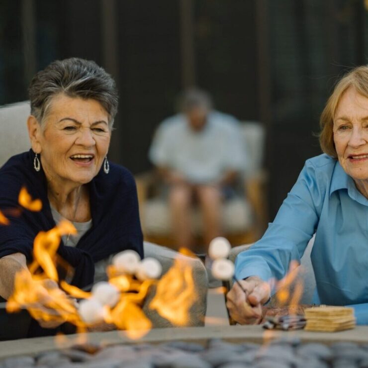 Lively seniors enjoy roasting marshmallows by the warm fire, fostering friendship and joy.