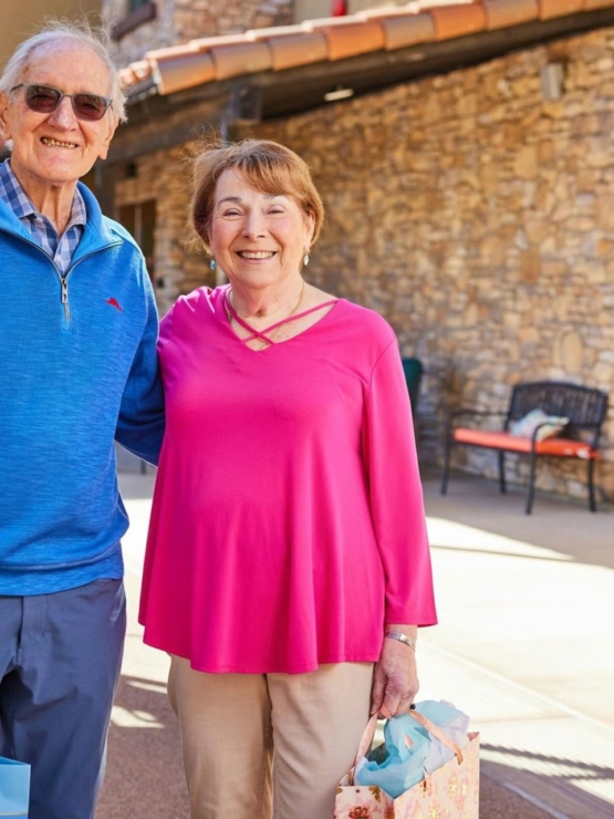 A joyful couple smiles warmly outdoors, embodying community spirit and shared moments of happiness.
