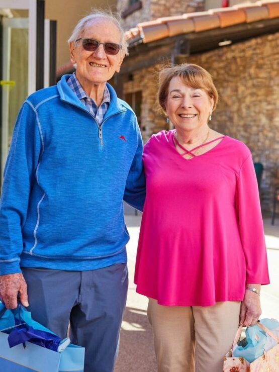 A joyful couple smiles warmly outdoors, embodying community spirit and shared moments of happiness.