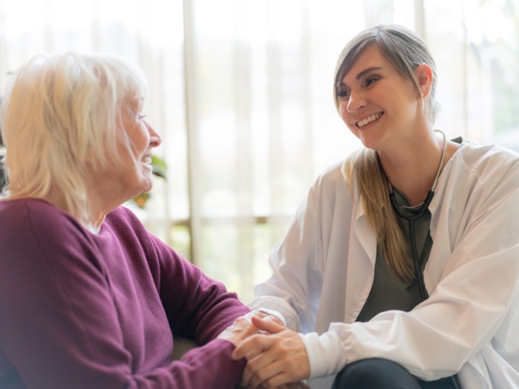 A tender moment between a caregiver and resident, fostering connection in a bright, inviting space.
