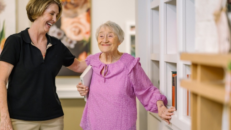 A warm moment of connection showcases a caring staff member and a joyful resident in a vibrant communal space.