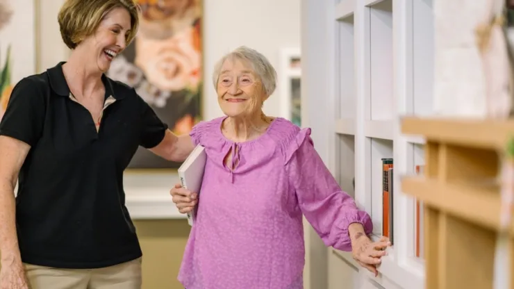 A warm moment of connection showcases a caring staff member and a joyful resident in a vibrant communal space.