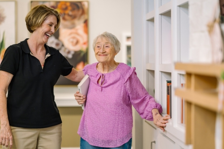 A warm moment of connection showcases a caring staff member and a joyful resident in a vibrant communal space.