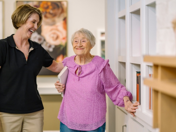 A warm moment of connection showcases a caring staff member and a joyful resident in a vibrant communal space.