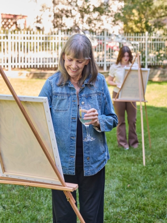 Residents enjoy art in a vibrant garden, fostering connection and creativity in a warm atmosphere.