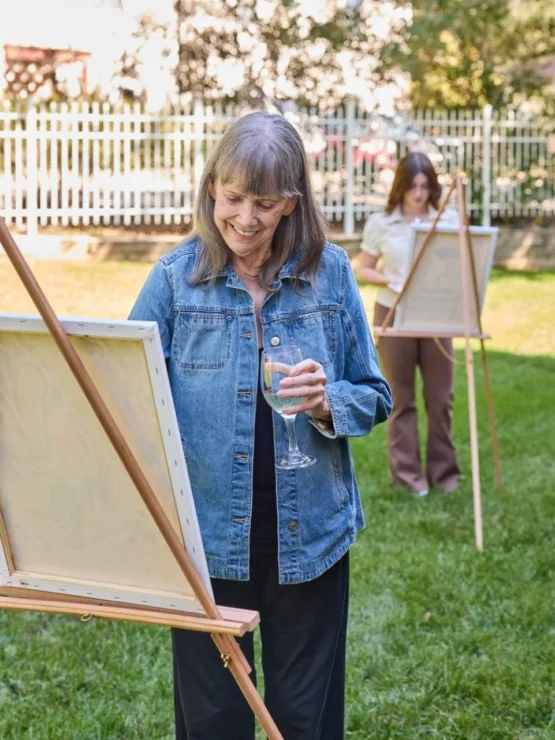 Residents enjoy art in a vibrant garden, fostering connection and creativity in a warm atmosphere.
