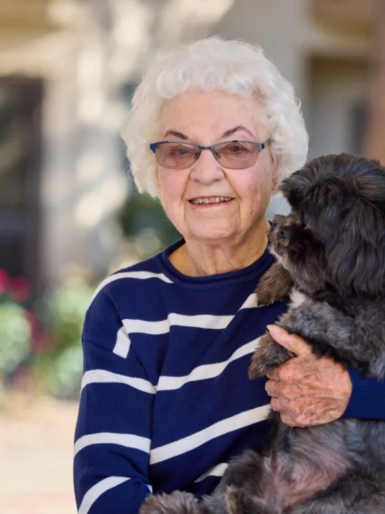 A smiling resident enjoying quality time with a furry friend in a vibrant, welcoming setting.