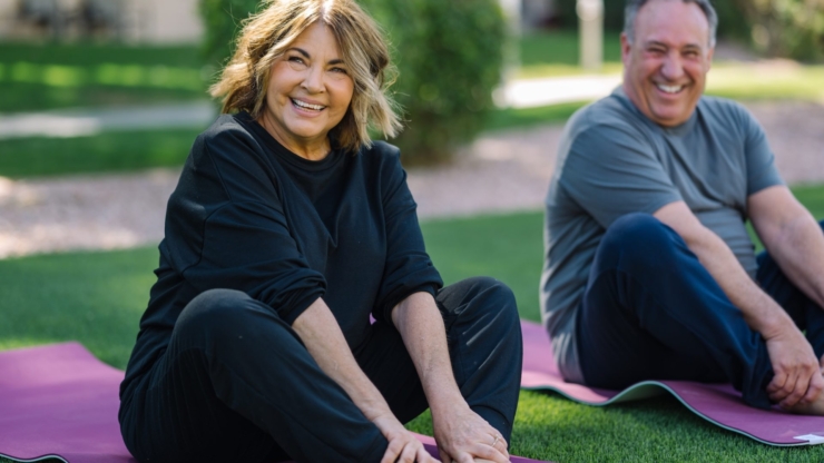 Lively individuals engage in yoga on vibrant mats, surrounded by greenery, sharing joy and connection.