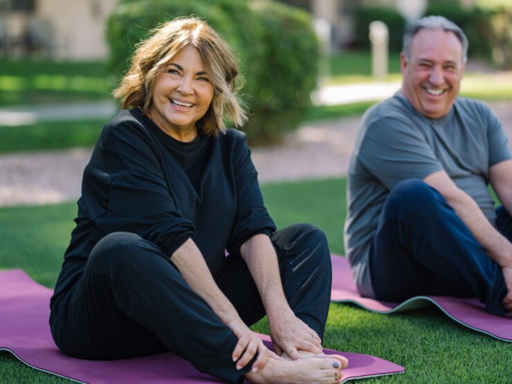Lively individuals engage in yoga on vibrant mats, surrounded by greenery, sharing joy and connection.