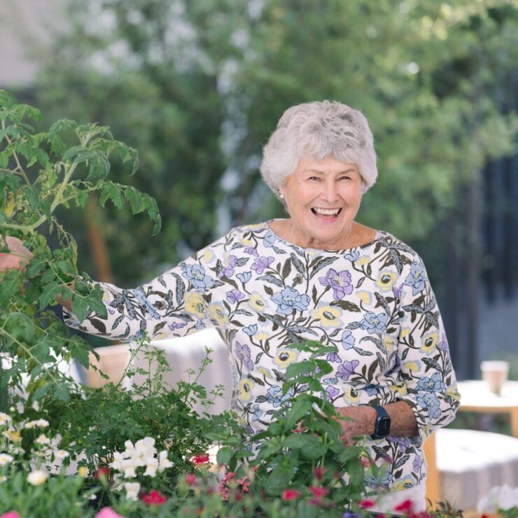 A joyful resident tends to vibrant flowers and plants, fostering a warm, nurturing community atmosphere.