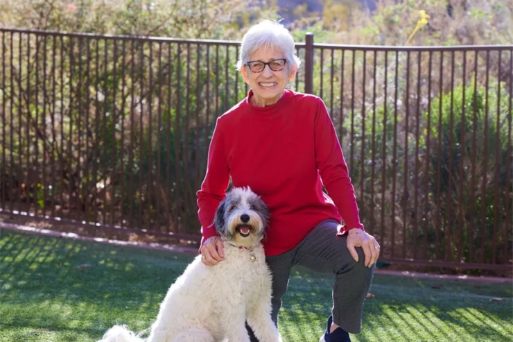 A cheerful resident enjoys quality time with a friendly dog in a vibrant, green outdoor space.