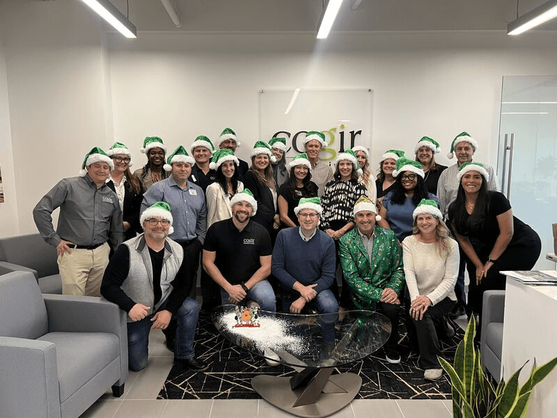A joyful group wearing festive hats gathers in a welcoming, modern space, radiating warmth and community spirit.