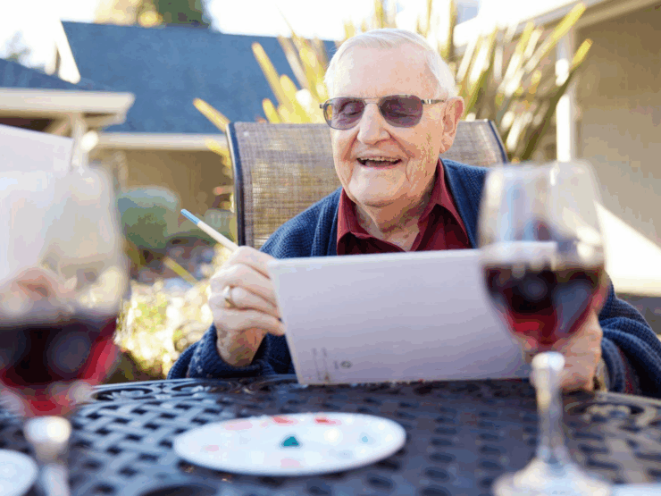 A cheerful resident enjoys painting outdoors, surrounded by friends and a warm, inviting atmosphere.