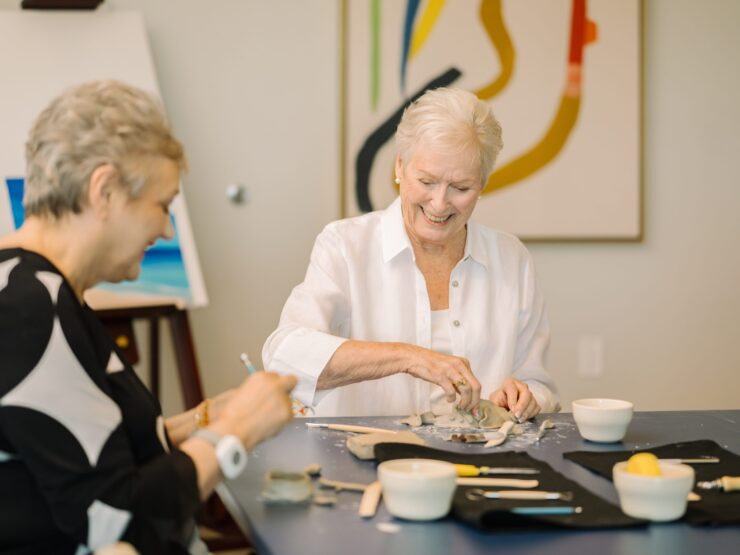 Two joyful residents engage in a creative pottery session, fostering community and connection.