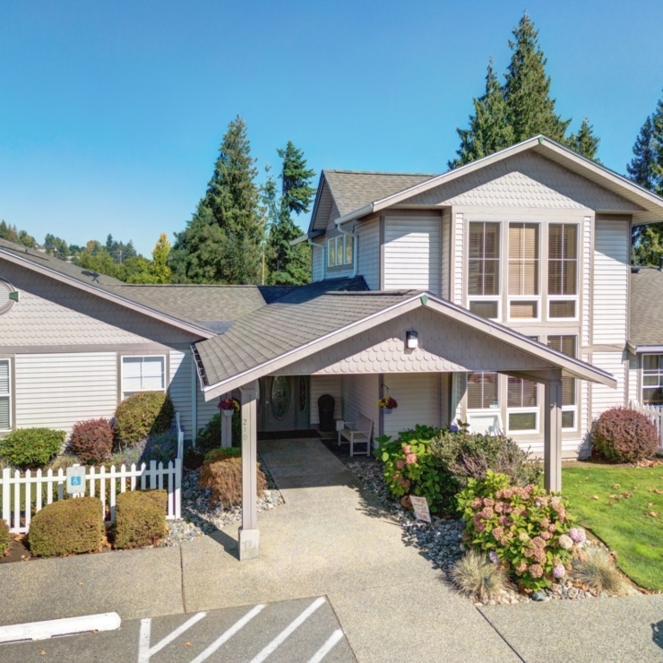 Bright, welcoming entrance surrounded by lush greenery, inviting residents to experience community and comfort.