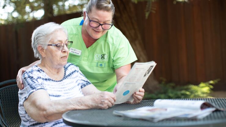 A caregiver warmly engages with a resident outdoors, fostering connection and joy in a serene setting.