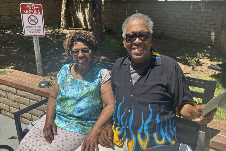 Two smiling residents enjoy a sunny day together, exuding warmth and community spirit in a serene outdoor setting.