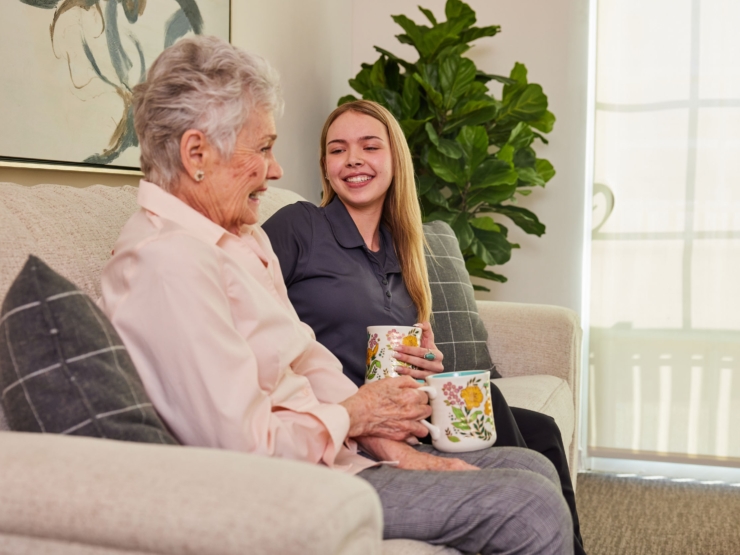 Two residents share a warm conversation over tea, surrounded by a bright, welcoming environment.