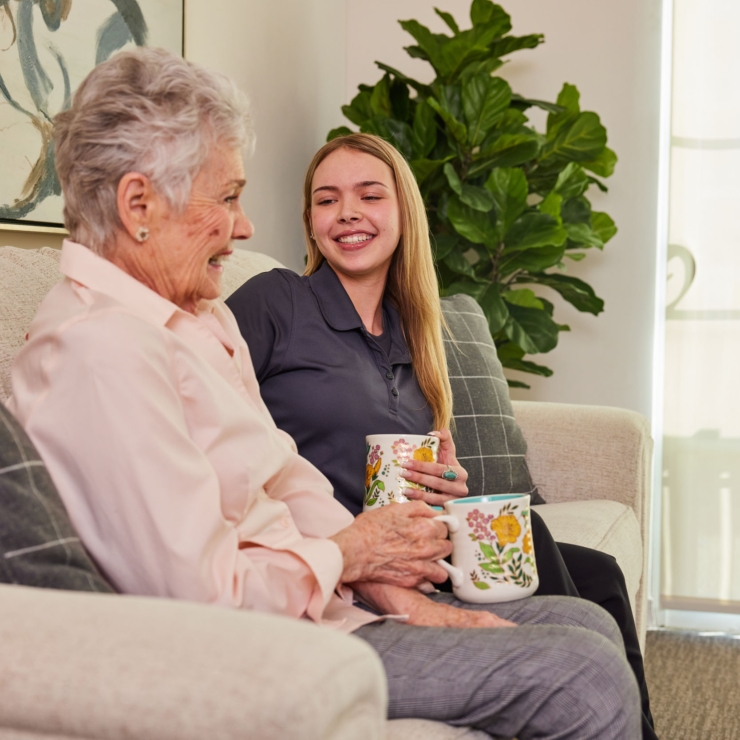 Two residents share a warm conversation over tea, surrounded by a bright, welcoming environment.