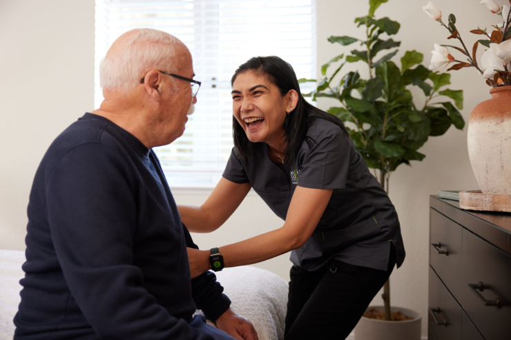 A cheerful caregiver shares a lighthearted moment with a resident, highlighting community and connection.
