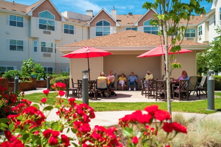 A vibrant outdoor gathering space filled with laughter, flowers, and friendly conversations under cheerful umbrellas.