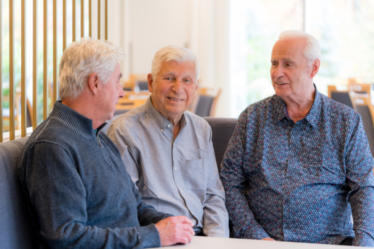 Three gentlemen share friendly conversation in a bright, inviting setting, fostering community and connection.