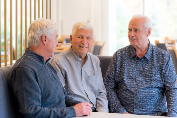 Three gentlemen share friendly conversation in a bright, inviting setting, fostering community and connection.