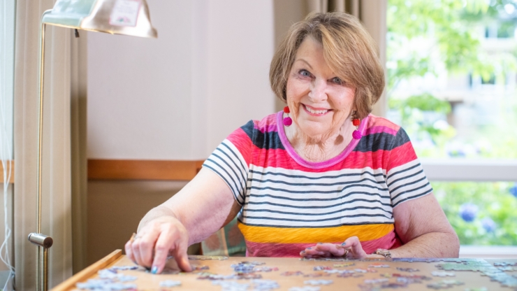A cheerful resident enjoys a puzzle, surrounded by natural light and a warm, inviting atmosphere.