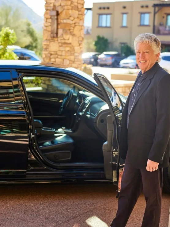 A welcoming atmosphere with a smiling gentleman near a stylish car, surrounded by a serene community.