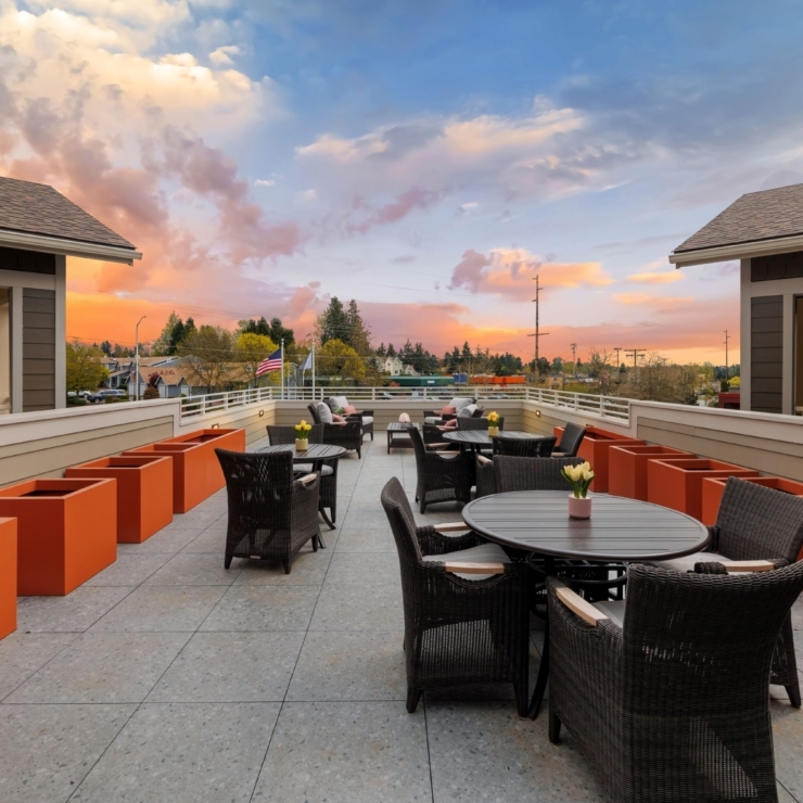 Inviting outdoor space with cozy seating, vibrant planters, and a stunning sunset backdrop.